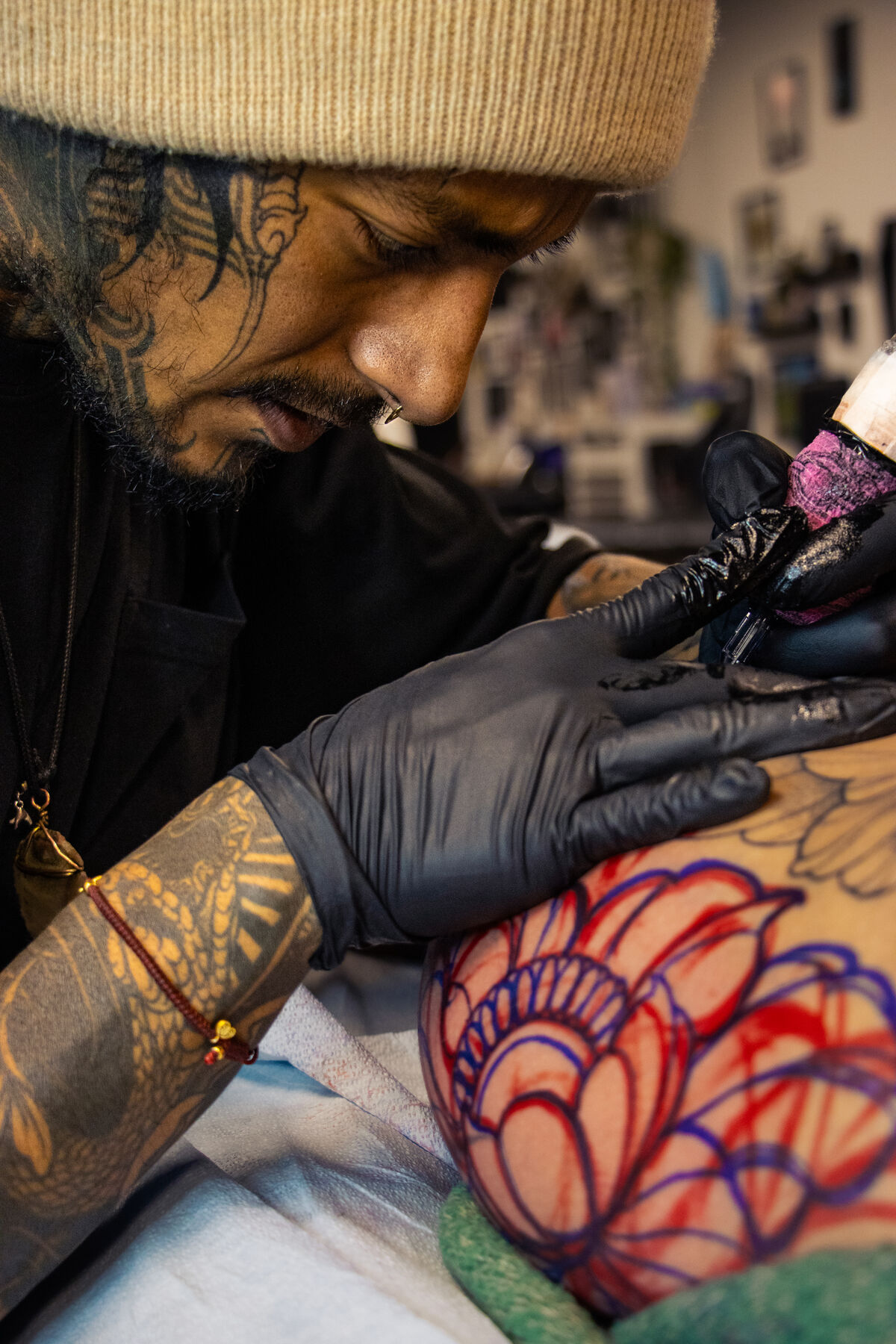 Close view of the artist tattooing over a red and blue lotus stencil
