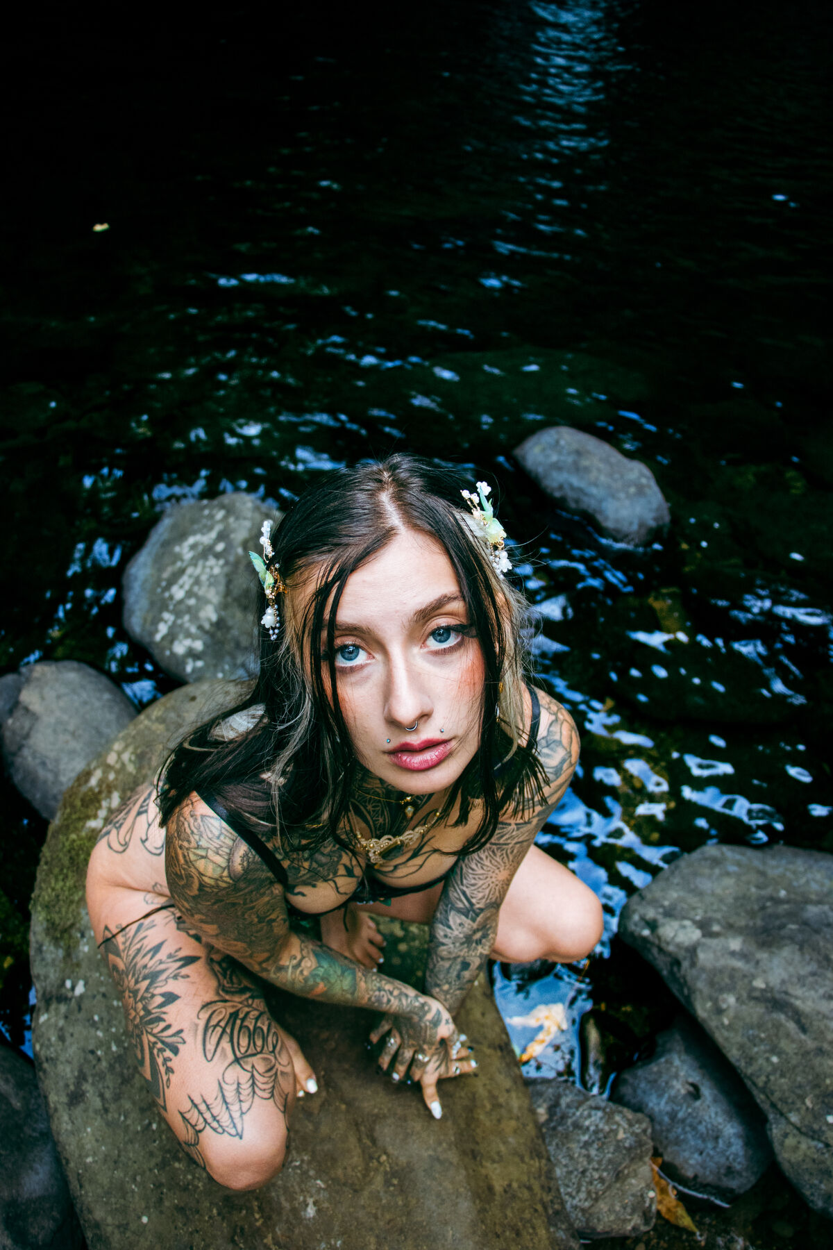 Portrait from above of Ali on river stones looking at the camera