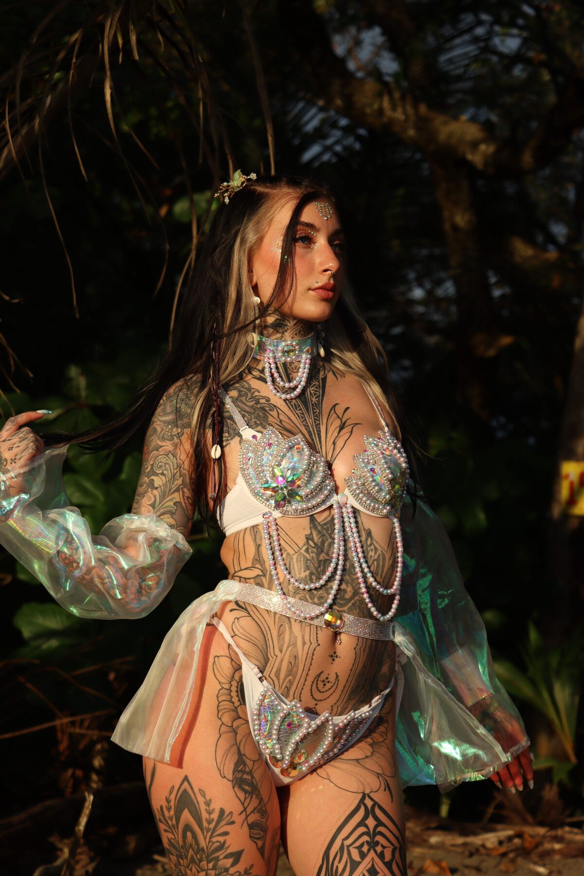 Ali in a pearl and shell top with iridescent sleeves among palms at golden hour